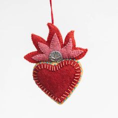 a red heart ornament hanging from a string on a white background with the shape of a flower