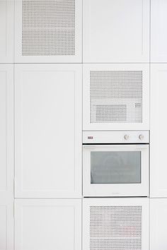 a white kitchen wall with an oven built into it's side by side cabinets