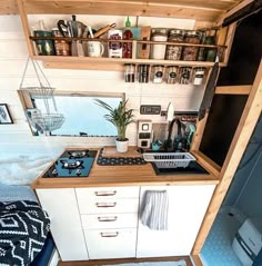 a small kitchen with an oven, sink and shelves on the wall above it in a tiny home