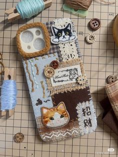 there is a cell phone case made out of fabric and other sewing supplies on the table