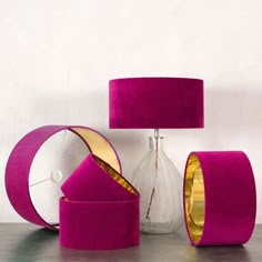 pink and gold furniture is sitting on a table next to a vase with a lamp