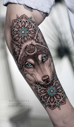 a person with a tattoo on their arm that has a wolf and flowers on it