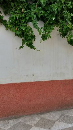 a red fire hydrant sitting next to a wall covered in green leaves and vines