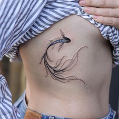 a woman's stomach with a fish tattoo on her belly and the bottom part of her body