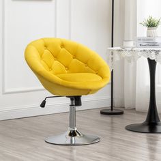 a yellow chair sitting on top of a hard wood floor next to a white table