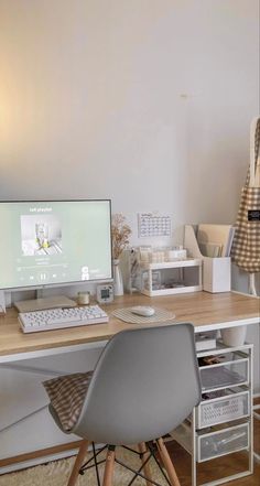 a desk with a computer, chair and other office supplies on top of it in front of a white wall