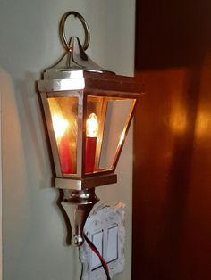 a light that is on the side of a wall with two candles attached to it