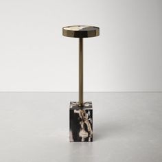 a black and white marble topped table with a gold metal stand in the middle on a plain surface