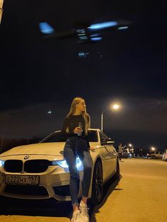 a woman sitting on the hood of a white car