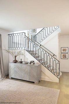 a living room with white walls and a stair case in front of the staircase leading up to the second floor