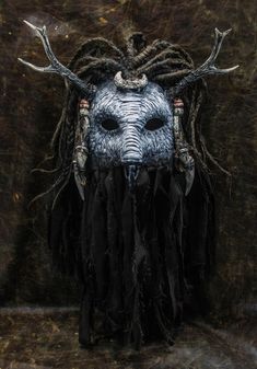 an animal mask with long hair and horns on it's head, in front of a brown background