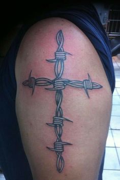 a cross tattoo with barbed wire on the arm