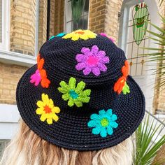 a woman wearing a black crocheted hat with colorful flowers on the brim