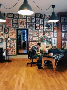 a man sitting at a desk in front of a wall covered with pictures and lights