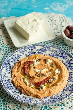 a plate with hummus and olives next to a bowl of feta cheese