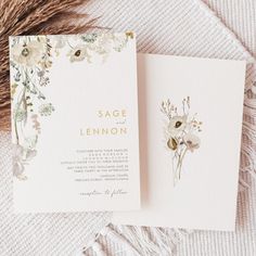 the wedding stationery is laid out on a white blanket with flowers and greenery