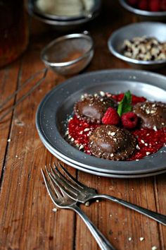 a plate with chocolate covered strawberries and raspberries on it next to silverware