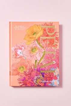 an orange book with flowers on the cover and chinese characters written in gold lettering, against a pale pink background