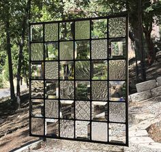 a large mirror sitting on the side of a road next to a tree filled forest