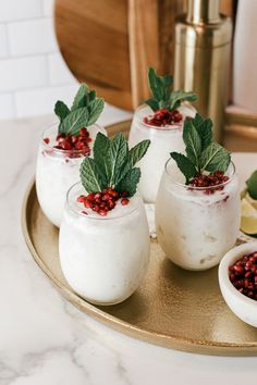 three glasses filled with yogurt and garnish on a tray