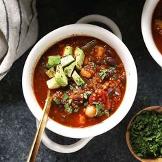 two bowls of chili and avocado soup on a table