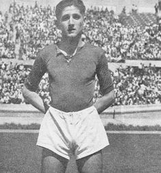 an old black and white photo of a man standing in front of a stadium full of people