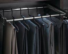 an open closet with clothes hanging on the rails and folded pants in front of it