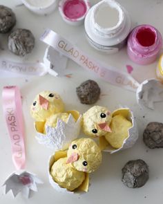 some little chicks are sitting in an egg carton with paint and glue on it