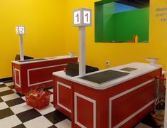 two red and white checkered floored booths with numbers on them in a yellow room