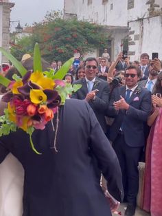 a group of people standing around each other in front of a building with flowers on their heads