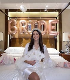 a woman sitting on top of a white bed in a room filled with balloons and decorations