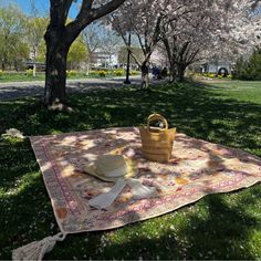 a picnic blanket with a straw hat on it in the grass next to a tree