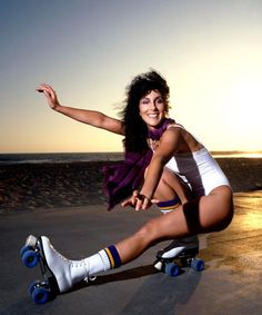 a woman riding a skateboard on top of a sandy beach