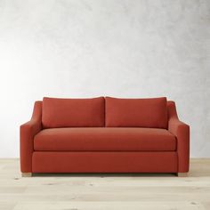 an orange couch sitting on top of a hard wood floor next to a white wall