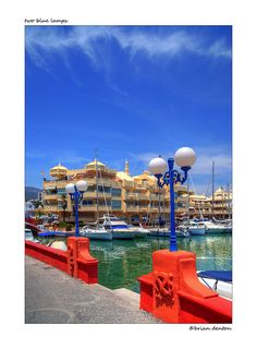 an orange and blue lamp post in front of a marina with boats docked on the water