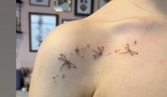 the back of a woman's shoulder with two small dragon tattoos on her left shoulder