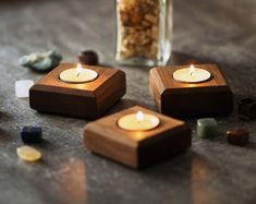 three tea lights sitting on top of a table next to some rocks and nuts in a jar