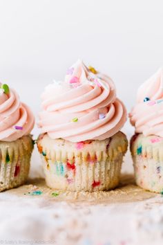 three cupcakes with pink frosting and sprinkles