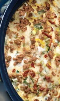 a blue casserole dish with meat and vegetables in it sitting on a table