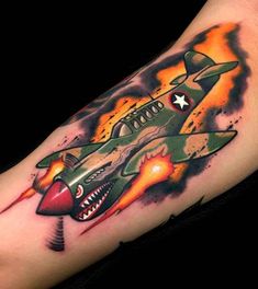 an old style fighter jet tattoo on the right arm and shoulder with flames coming out of it