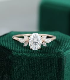 a diamond ring sitting on top of a green velvet box