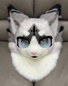 a white and gray cat with blue eyes sitting on a couch