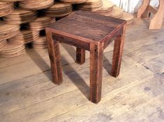 a small wooden table sitting in front of stacks of stacked wood plates on the floor