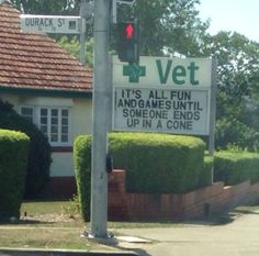 a traffic light sitting on the side of a road next to a sign that says vet it's all fun and games until up in a cone