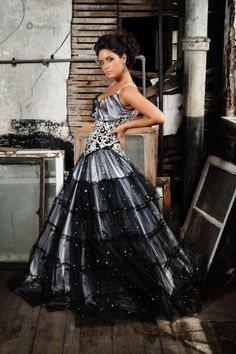 a woman in a black and silver dress standing on a wooden floor next to an oven