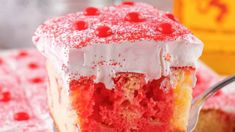 a piece of red velvet cake with white frosting and cherries on top is being held by a fork