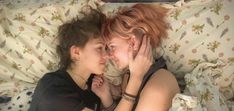 two women laying in bed with their faces close to each other