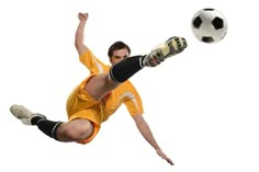 a man kicking a soccer ball in the air with his legs spread out to catch it