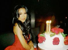 a woman sitting in front of a cake with candles on it and roses around the edges