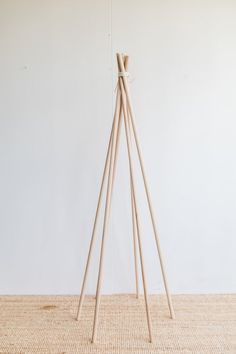 three wooden sticks are standing in front of a white wall with a light colored floor